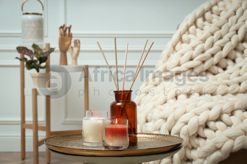 Air reed freshener and burning candles on table indoors. Interior elements