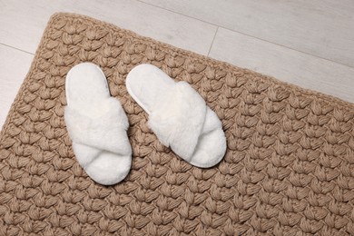 Photo of Soft white slippers on carpet in room. Space for text