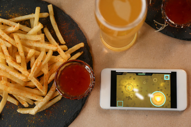 Flat lay composition with smartphone and french fries on table
