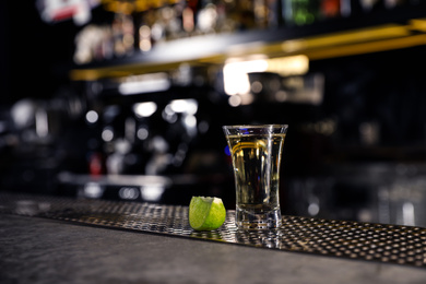 Mexican Tequila shot with lime slice on bar counter. Space for text