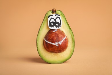 Avocado with drawn face on orange background. Exhibitionist concept