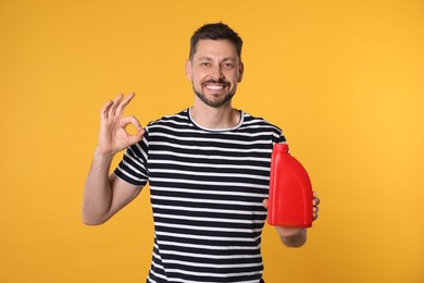Man holding red container of motor oil and showing OK gesture on orange background