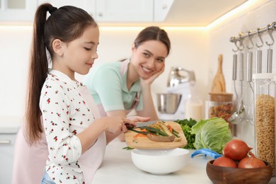 Photo of Mother and daughter peeling vegetables at kitchen counter