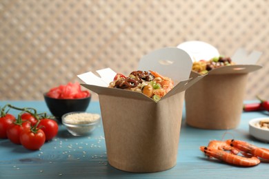 Boxes of wok noodles with seafood on light blue wooden table