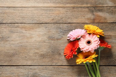 Beautiful colorful gerbera flowers on wooden table, flat lay. Space for text
