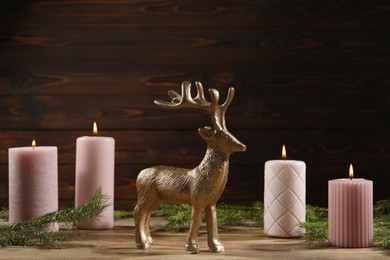 Beautiful deer figure and burning candles on wooden table