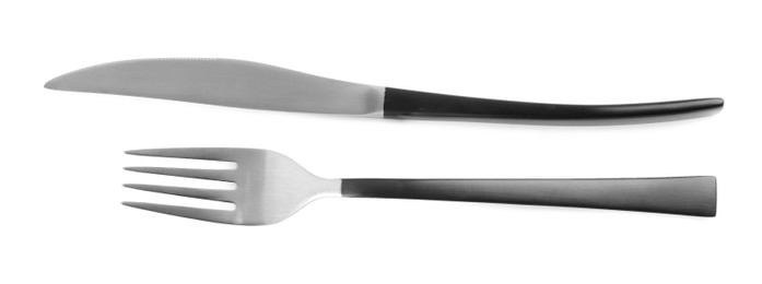 New fork and knife with black handles on white background, top view