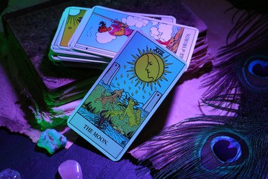 Moon and other tarot cards with old book on dark table, color toned