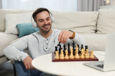 Photo of Teacher near chessboard conducting online lesson at home. Time for hobby
