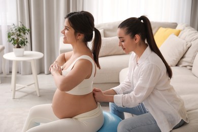 Doula working with pregnant woman in living room. Preparation for child birth
