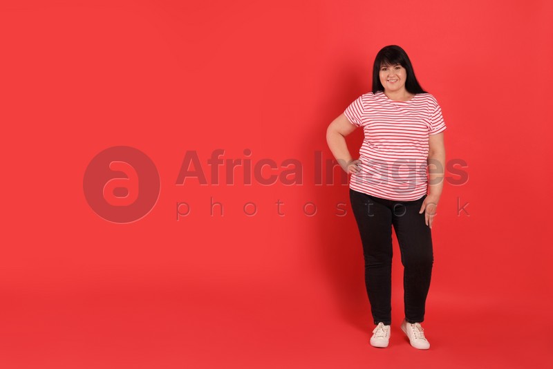 Beautiful overweight mature woman with charming smile on red background. Space for text