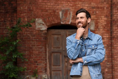 Smiling handsome bearded man looking away outdoors. Space for text