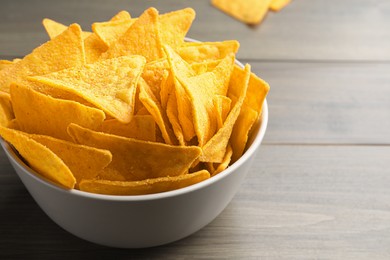 Photo of Tortilla chips (nachos) in bowl on wooden table, closeup