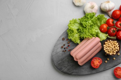 Fresh raw vegetarian sausages and vegetables on grey table, flat lay. Space for text