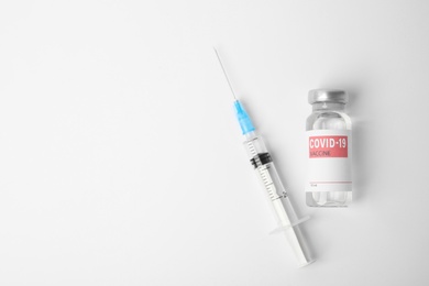Vial with coronavirus vaccine and syringe on white background, flat lay. Space for text
