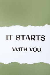 Sheet of paper with phrase It Starts With You on green background, top view