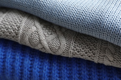 Photo of Stack of folded warm knitted sweaters, closeup