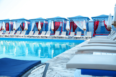 Outdoor swimming pool and sunbeds at resort on sunny day