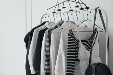 Rack with stylish clothes near white wall, closeup