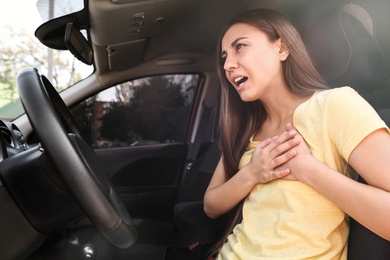 Young woman suffering from heart attack in car