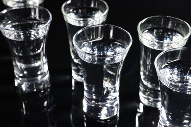 Shot glasses with vodka on black table