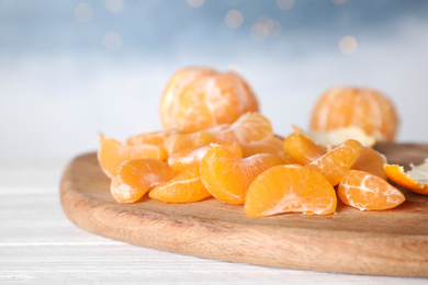 Segments of fresh juicy tangerines on white wooden table, closeup