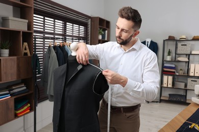 Photo of Tailor working with unfinished suit jacket in atelier