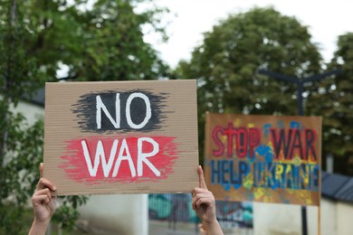 Woman holding poster with words No War outdoors, closeup