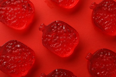 Delicious gummy pomegranate candies on red background, flat lay