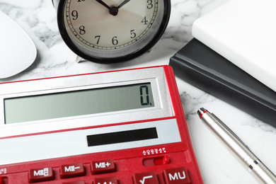 Calculator, alarm clock and notebooks on marble table, closeup. Tax accounting