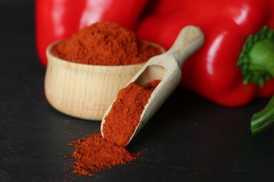 Paprika powder and fresh bell peppers on black table, closeup