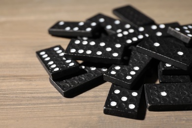 Black domino tiles on wooden table, closeup