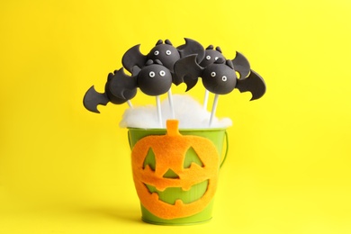 Delicious bat shaped cake pops on yellow background. Halloween treat