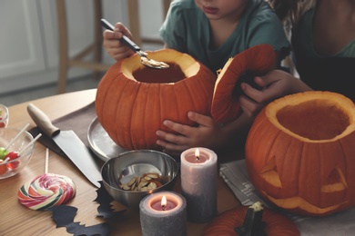 Mother and daughter making pumpkin jack o'lantern at table, closeup. Halloween celebration