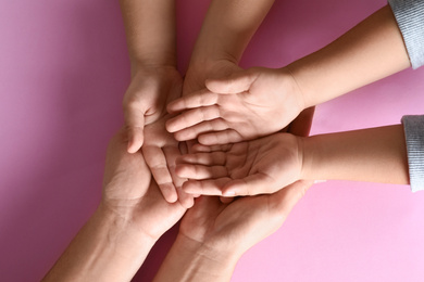Happy family holding hands on pink background, top view