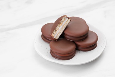 Saucer with delicious choco pies on white table