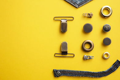 Flat lay composition with garment accessories and cutting details for jeans on yellow background. Space for text