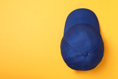 Stylish blue baseball cap on yellow background, top view. Space for text