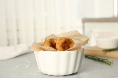 Delicious crunchy fried onion rings on grey marble table indoors