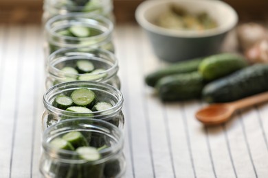 Set of glass jars with fresh cucumbers prepared for canning on table, closeup. Space for text