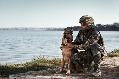 Image of Man in military uniform with German shepherd dog near river, space for text
