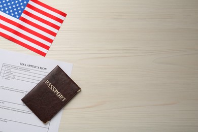 Photo of American flag, visa application form and passport on white wooden table, flat lay. Space for text