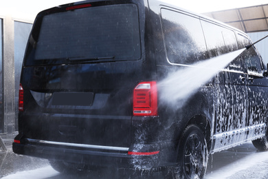 Cleaning automobile with high pressure water jet at car wash