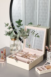 Elegant jewelry boxes with expensive wristwatches and beautiful bijouterie on grey table in room