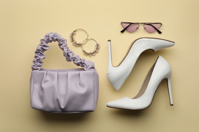 Stylish woman's bag, shoes, earrings and sunglasses on beige background, flat lay