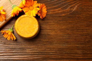 Photo of Yellow solid shampoo bar and flowers on wooden table, flat lay. Space for text