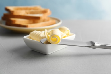 Knife and gravy boat with butter curls on table