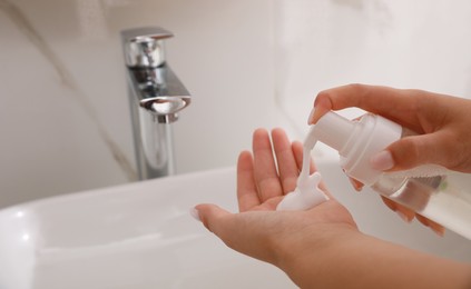 Teenage girl using cleansing foam in bathroom, closeup. Skin care cosmetic