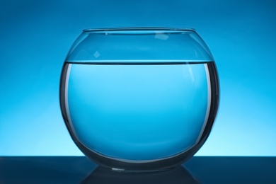 Round fish bowl filled with water on blue background