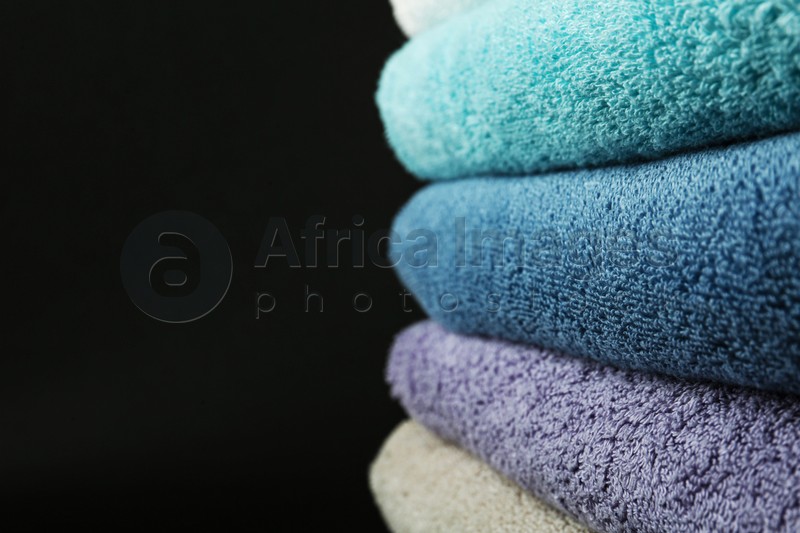 Different fresh soft terry towels on dark background, closeup. Space for text